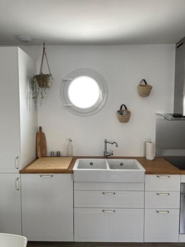 een witte keuken met een wastafel en een raam bij Les Lodges de Saint Brice 1 in Arès