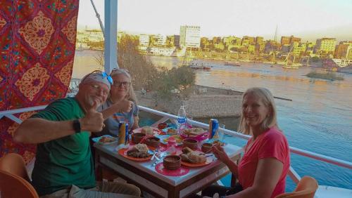 um grupo de pessoas sentadas à mesa com comida em Kana Kato em Aswan