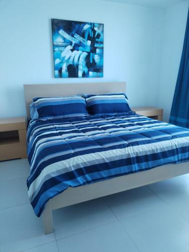 a bed with a blue and white blanket and pillows at suplayablanca Río Hato Antón Coclé in Loma del Naranjo