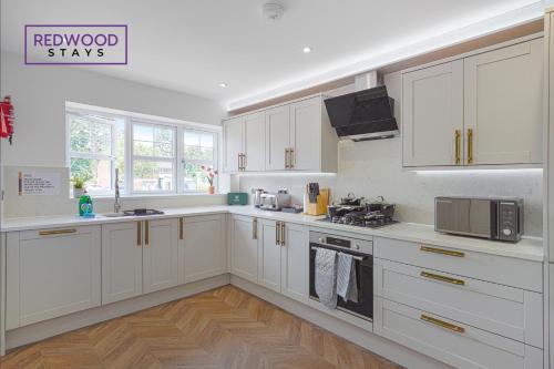 a large white kitchen with white cabinets and appliances at Spacious 4 Bedroom 2 Bath Serviced Home For Contractors & Families with X2 Free Parking Spaces, Fast WiFi - Hosted By Redwood Stays in Farnborough