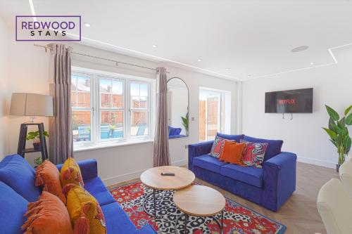 uma sala de estar com um sofá azul e uma mesa em BRAND NEW Spacious 4 Bedroom Houses For Contractors & Families with FREE Parking, Garden, Fast Wifi and Netflix By REDWOOD STAYS em Farnborough