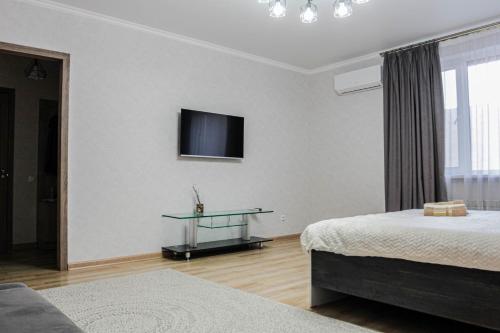 a bedroom with two beds and a tv on the wall at Apartment Arman Kala at left coast in Astana in Prigorodnyy