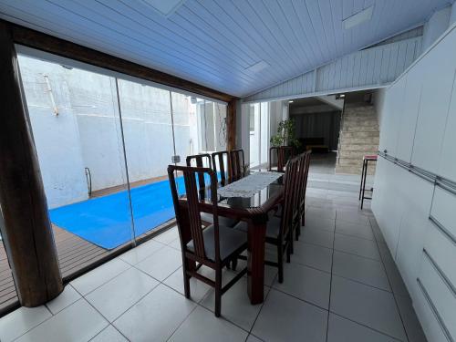 a dining room with a table and chairs and a pool at Casa com Piscina em Xangri-Lá RS in Xangri-lá