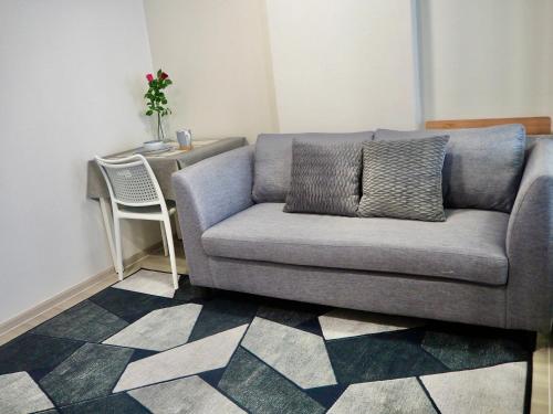 a gray couch in a living room with a table at Cozy room, BKK for short and long term rentals, 10mins walk to BTS, 25mins taxi to DMK airport in Ban Ko