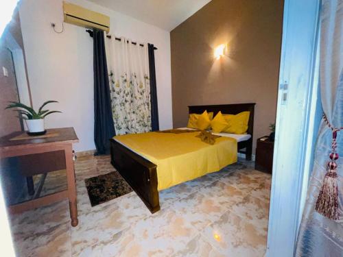 a bedroom with a bed with yellow sheets and a table at Winston Dutch Canal Villa Guest House in Negombo