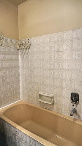 La salle de bains est pourvue d'une baignoire et de carrelage blanc. dans l'établissement Proche Croisette, T2 avec terrasse, By Palmazur, à Cannes