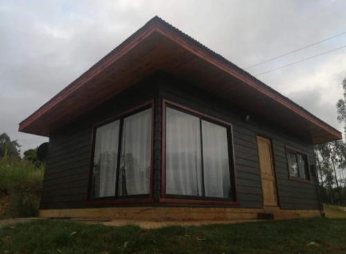 Casa pequeña con ventanas grandes en el césped en Spa el mirador/ Cabaña y Centro de Eventos, en Quechupulli