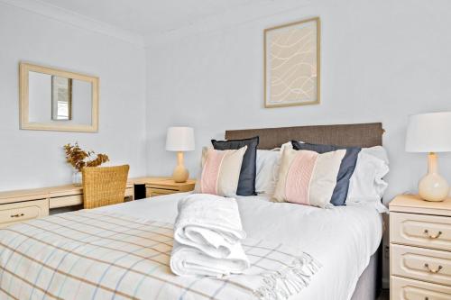um quarto com uma cama com lençóis brancos e almofadas em Bramcote Lane Spacious 5 BR House em Nottingham