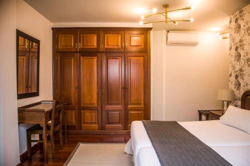 a bedroom with a bed and a desk and a table at Hotel A Casa Do Rio in Padrón