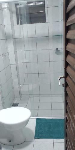 a white bathroom with a toilet and a shower at Apto 03 - 1 quarto com 2 camas solteiro e garagem, possui ventilador de teto in Cascavel