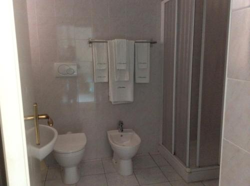 a white bathroom with a toilet and a sink at Hotel Edera in Procchio