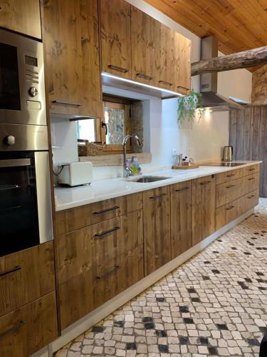 a kitchen with wooden cabinets and a sink at Adega D'Aldeia com piscina e jacuzzi in Ulmeiro