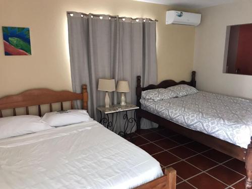 a bedroom with two beds and a window at Bamboleo Inn in Belize City