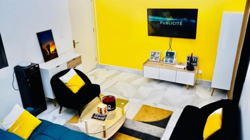 a living room with a blue couch and a yellow wall at Grand Appartement LUXE secteur Mamelles et Monument de la renaissance in Ouakam