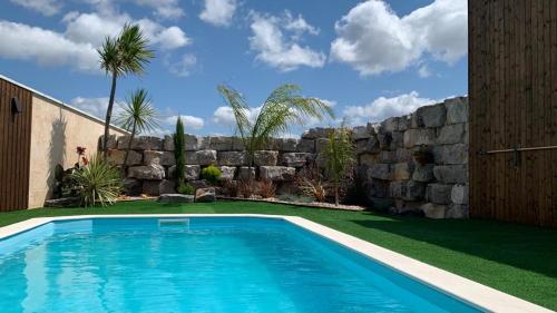 a swimming pool in a yard next to a stone wall at Adega D'Aldeia 