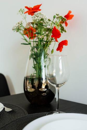a vase with red flowers next to a wine glass at Pokoje Na Winklu in Kluszkowce