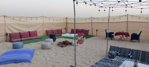 a tent with chairs and tables in the sand at RVS Caravan Desert Resort Dubai in Hunaywah