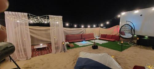a tent with a couch in the sand with lights at RVS Caravan Desert Resort Dubai in Hunaywah