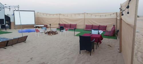 a tent with tables and chairs in the sand at RVS Caravan Desert Resort Dubai in Hunaywah