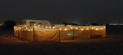 a large fence with lights on it at night at RVS Caravan Desert Resort Dubai in Hunaywah