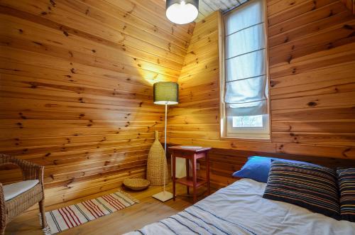 a bedroom with wooden walls and a bed and a window at Domki na Polach Piwniczna-Zdrój in Piwniczna