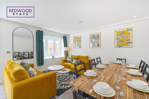uma sala de jantar com uma mesa de madeira e cadeiras amarelas em BRAND NEW Spacious 4 Bedroom Houses For Contractors & Families with FREE Parking, Garden, Fast Wifi and Netflix By REDWOOD STAYS em Farnborough