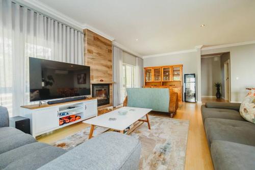 a living room with a couch and a tv and a table at Sidwell Gardens, Adjacent to Kingswood Estate in George