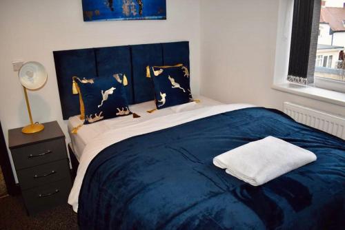 a bedroom with a large bed with blue sheets and pillows at Beeston House 3 BR and FREE Parking in Beeston
