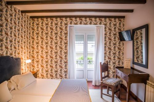 a bedroom with a bed and a desk and a window at Hotel A Casa Do Rio in Padrón
