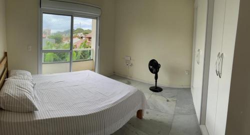 a white bedroom with a bed and a window at Apartamento Praia da Cal in Torres