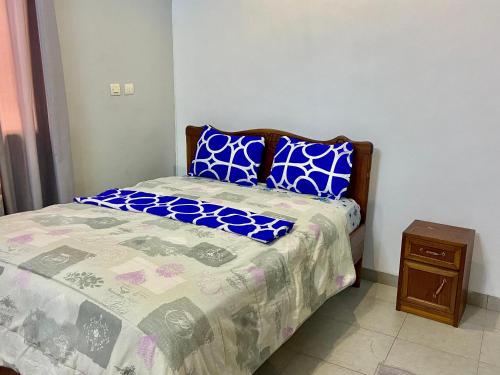 a bedroom with a bed and a night stand at Appartement hôte + in Ouagadougou