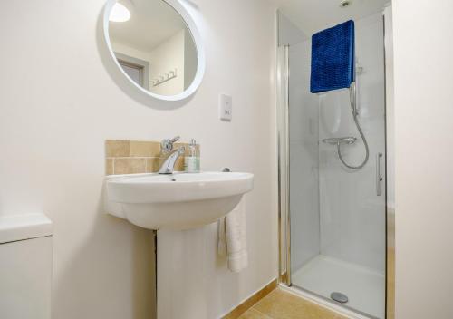 ein weißes Bad mit einem Waschbecken und einer Dusche in der Unterkunft Half Moon Cottage in West Runton