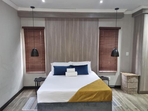 1 dormitorio con 1 cama grande con almohadas azules en The Packwood Cottage, en Johannesburgo