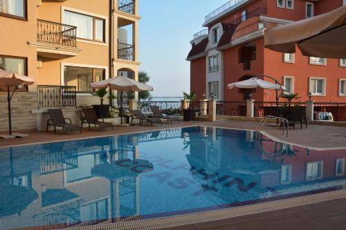 a swimming pool with chairs and umbrellas next to some buildings at VIP CLUB Dolphin Coast in Sunny Beach