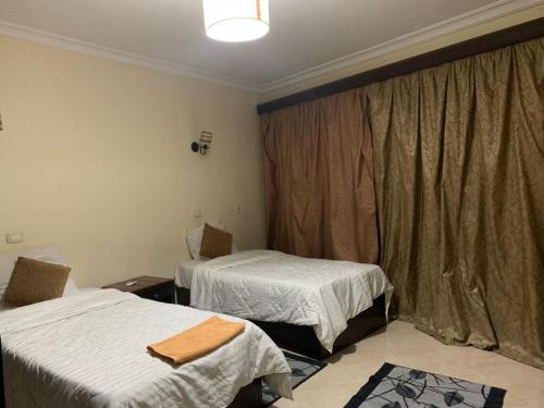 Cette chambre comprend deux lits et une fenêtre avec des rideaux. dans l'établissement Sheraton apart-hotel, au Caire