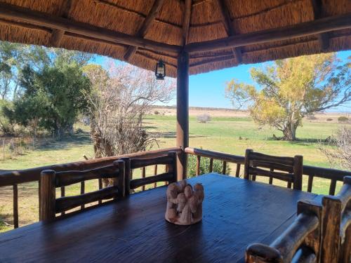 - une table sur une terrasse couverte avec vue sur un champ dans l'établissement Garingboom Guest Farm, à Springfontein