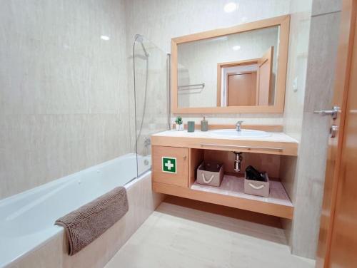 a bathroom with a sink and a mirror and a tub at Mountain View Club Faia in Portimão