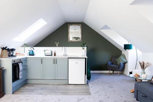 a kitchen with white cabinets and a roof at Emerald Lodge in Puddletown