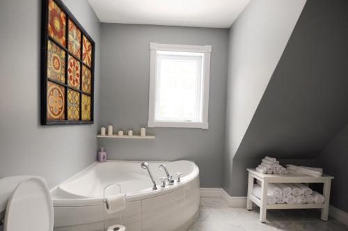 een badkamer met een wit bad en een raam bij Chalet LExcentrique SPA et Nature in Mandeville