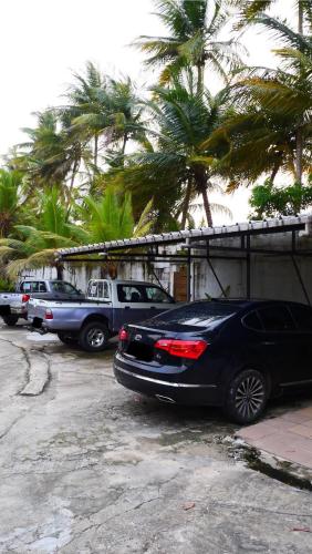 a row of cars parked in a parking lot with palm trees at Résidence Tropicale in Libreville