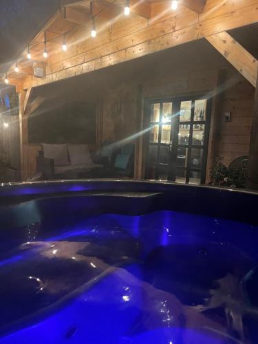 een groot blauw bad in een kamer met een bed bij O Dan Y Coed Swedish Log Cabin with New 2024 Wood Fired Hot Tub in Chwilog
