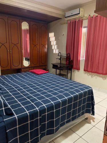 Schlafzimmer mit einem blauen Bett und roten Vorhängen in der Unterkunft Casa Edgar in Manaus