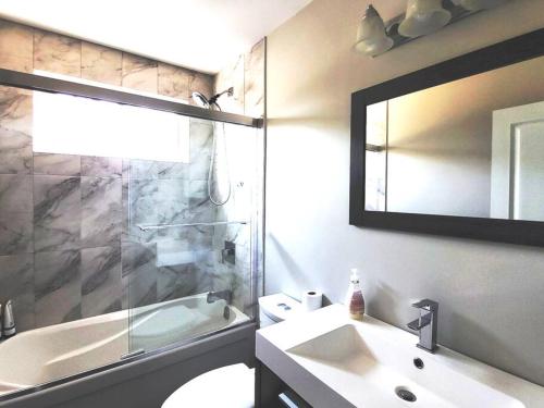 La salle de bains est pourvue d'un lavabo, d'une douche et d'un miroir. dans l'établissement Cozy Home in Niagara-on-the-Lake, à Niagara on the Lake