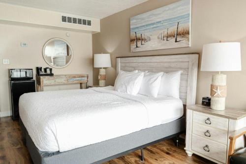 Un dormitorio con una gran cama blanca y un espejo. en Lavish 4th Floor Oceanfront King Room, en Pawleys Island
