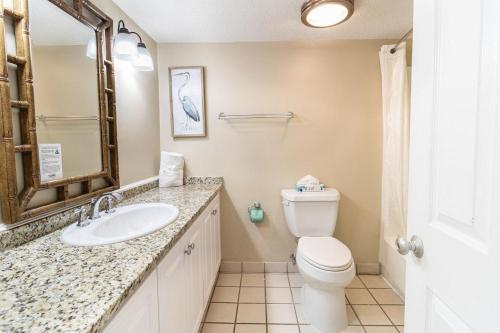 Un baño con inodoro, lavabo y espejo. en Lavish 4th Floor Oceanfront King Room, en Pawleys Island