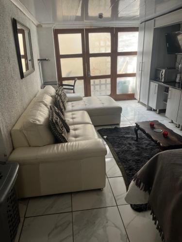 a living room with a white couch and a table at An elegant stay away from home in Johannesburg