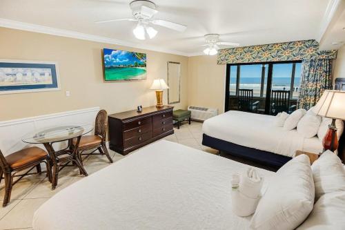 a hotel room with two beds and a table and chairs at Bright and Beautiful Dunes Room 1st Floor in Pawleys Island