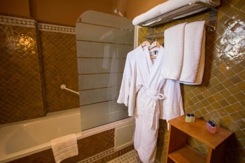 ein Bad mit Handtüchern, die auf einem Kleiderständer neben einer Badewanne hängen in der Unterkunft Riad Raouia HAMMAM & SPA in Fès