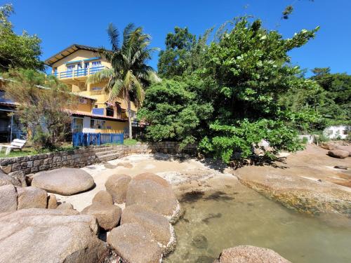 una casa con un árbol y rocas en el agua en Prainha da Nina Apartamentos, en Florianópolis