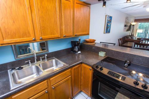 een keuken met houten kasten, een wastafel en een fornuis bij Emerald Isle Unit 211 in Fort Walton Beach